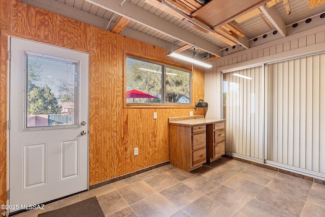 interior space with wooden ceiling, a wealth of natural light, beamed ceiling, and wooden walls