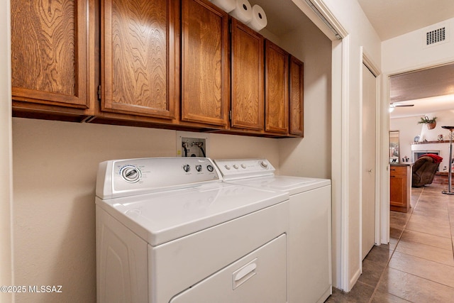 laundry area with light tile patterned floors, independent washer and dryer, and cabinets