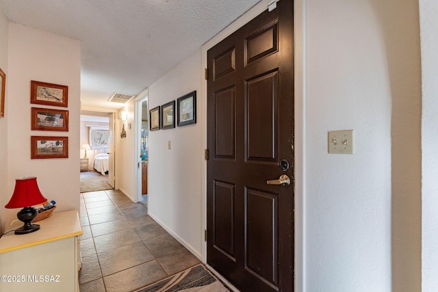 hall with a textured ceiling and tile patterned flooring