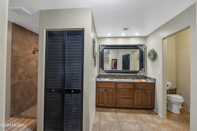 bathroom with toilet, vanity, and tile patterned flooring