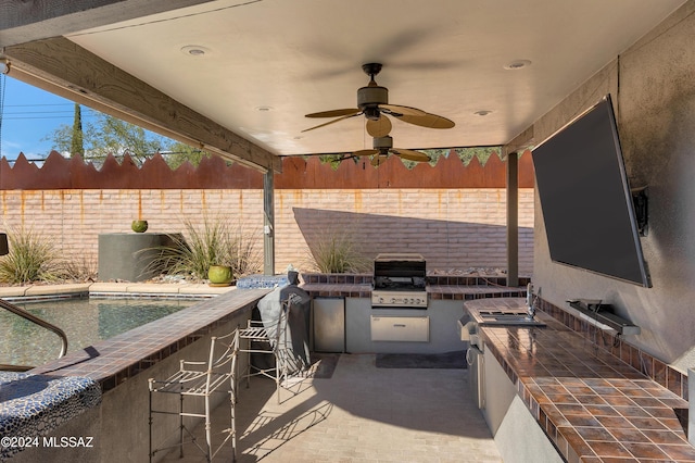 view of patio / terrace with ceiling fan, a grill, an outdoor kitchen, and exterior bar