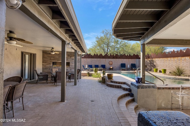 view of patio / terrace with ceiling fan, a bar, and a fenced in pool