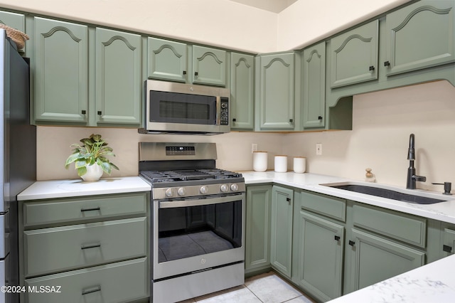 kitchen with light tile patterned floors, sink, appliances with stainless steel finishes, and green cabinets