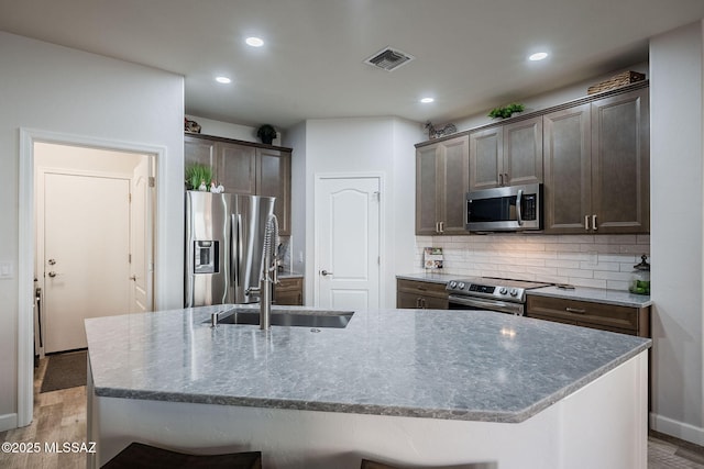 kitchen featuring sink, light hardwood / wood-style flooring, stainless steel appliances, and a kitchen island with sink