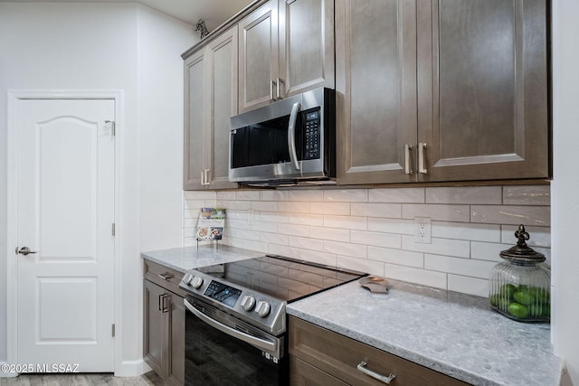 kitchen with tasteful backsplash, light stone countertops, and appliances with stainless steel finishes