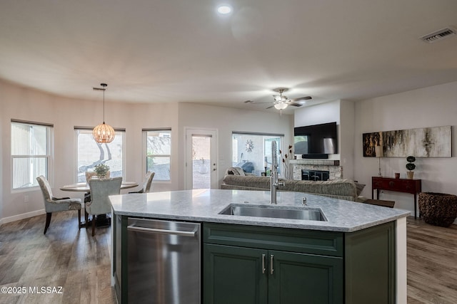 kitchen with dishwasher, a center island with sink, sink, hanging light fixtures, and dark hardwood / wood-style flooring