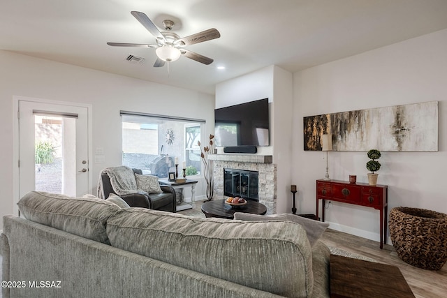 living room with ceiling fan, a fireplace, and hardwood / wood-style flooring