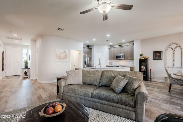 living room featuring ceiling fan, sink, and light hardwood / wood-style floors