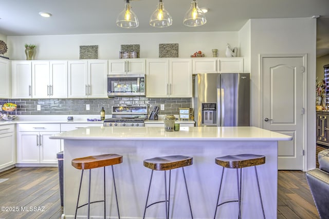 kitchen with stainless steel appliances, decorative backsplash, pendant lighting, and white cabinetry