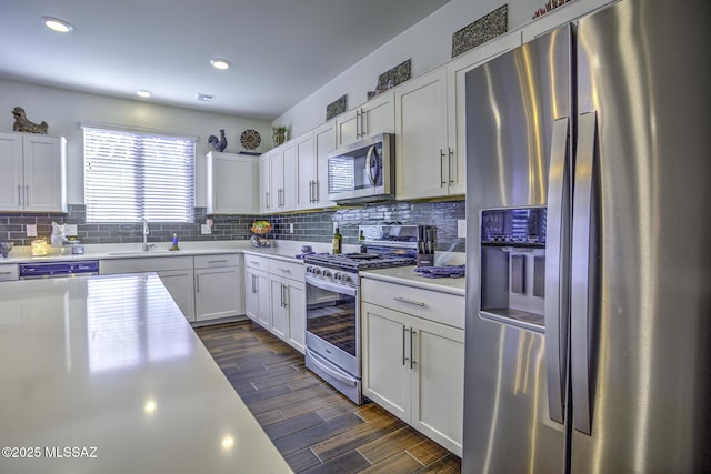 kitchen with appliances with stainless steel finishes, white cabinets, decorative backsplash, and sink