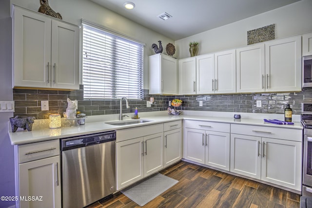 kitchen featuring stainless steel appliances, sink, white cabinets, decorative backsplash, and dark wood-type flooring