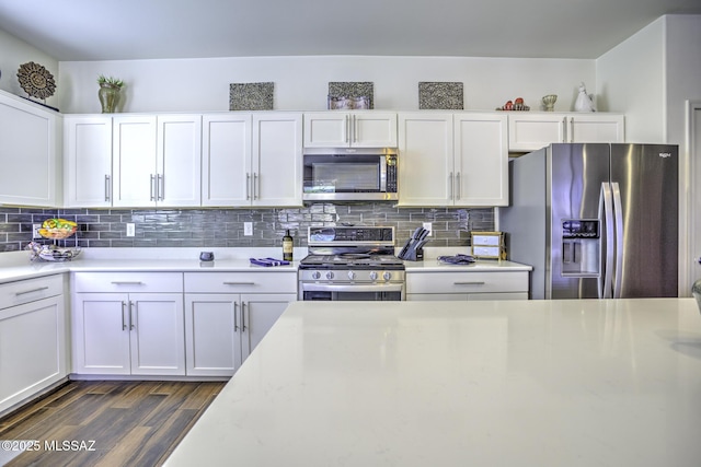 kitchen featuring white cabinets, appliances with stainless steel finishes, dark hardwood / wood-style floors, and decorative backsplash