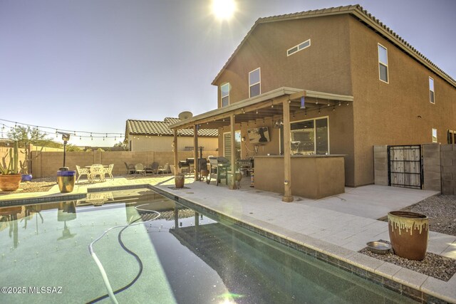 pool at dusk with an outdoor bar and a patio area