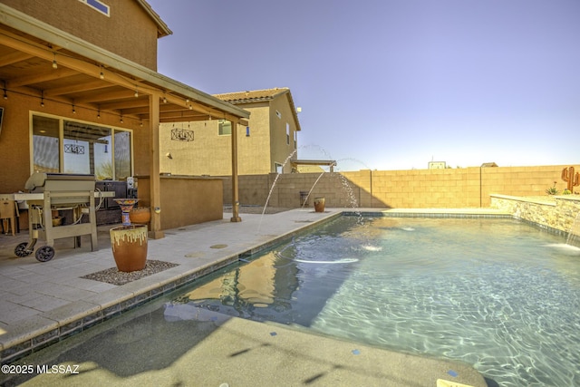 pool at dusk featuring a patio and pool water feature