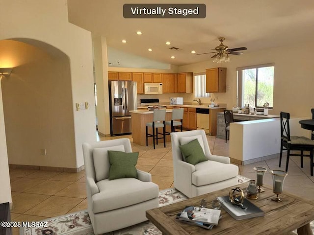 tiled living room with ceiling fan, lofted ceiling, and sink