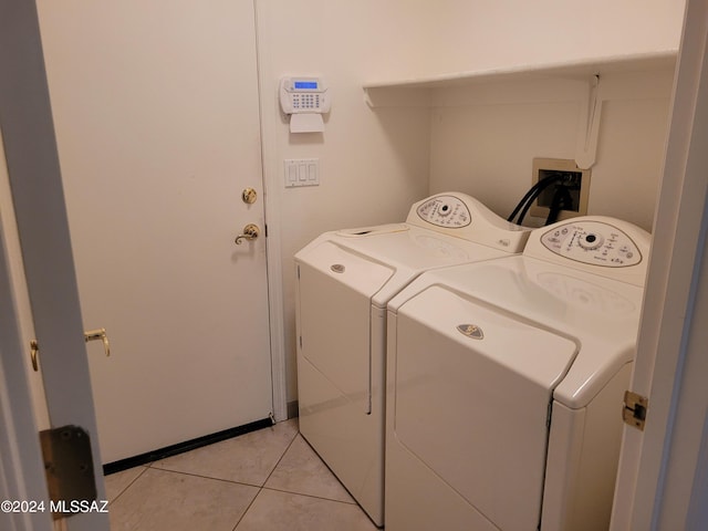 clothes washing area with washer and clothes dryer and light tile patterned floors