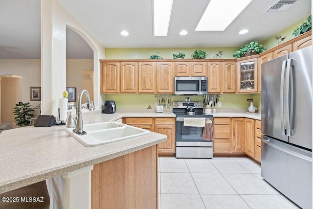 kitchen featuring appliances with stainless steel finishes, sink, hanging light fixtures, kitchen peninsula, and light tile patterned floors