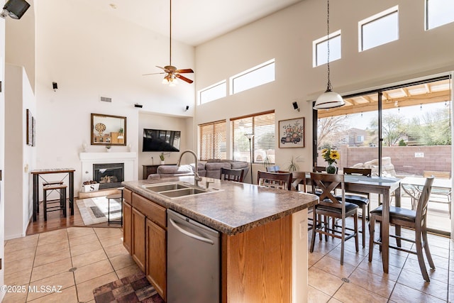 kitchen featuring sink, dishwasher, a kitchen island with sink, light tile patterned flooring, and decorative light fixtures