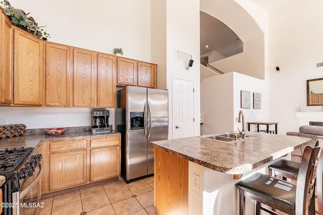 kitchen featuring sink, a breakfast bar, stainless steel appliances, a high ceiling, and a kitchen island