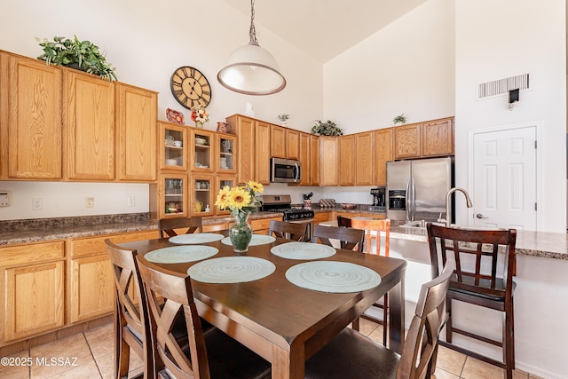 tiled dining space with sink and high vaulted ceiling