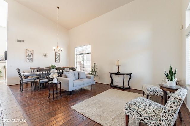 living room featuring dark hardwood / wood-style flooring, a notable chandelier, and high vaulted ceiling