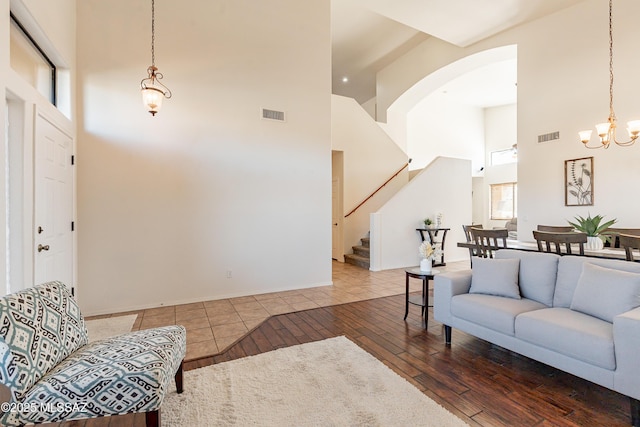 living room with an inviting chandelier, hardwood / wood-style floors, and a high ceiling