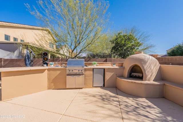 view of patio / terrace featuring exterior kitchen, an outdoor fireplace, and a grill