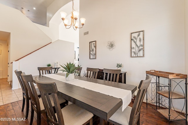 dining space with an inviting chandelier, dark wood-type flooring, and a high ceiling