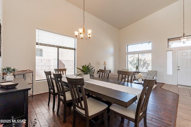 dining room with dark wood-type flooring, an inviting chandelier, and high vaulted ceiling