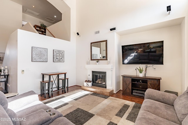 living room with a tiled fireplace, a high ceiling, and dark hardwood / wood-style floors