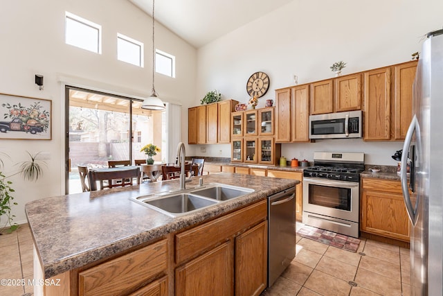 kitchen featuring sink, hanging light fixtures, appliances with stainless steel finishes, a healthy amount of sunlight, and a kitchen island with sink