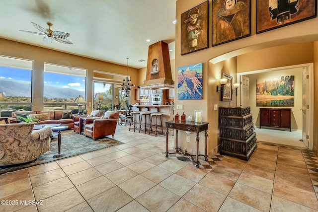 living room featuring light tile patterned floors, ceiling fan, a high ceiling, and arched walkways