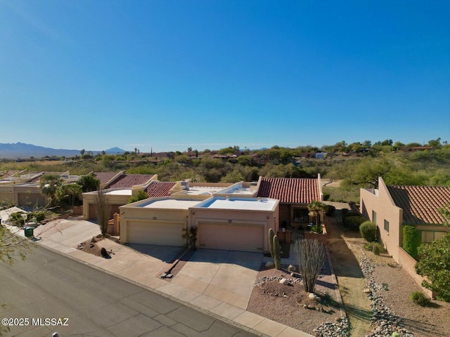 view of front facade featuring stucco siding, a mountain view, fence, a garage, and driveway