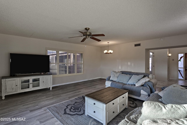 living room with a wealth of natural light, a textured ceiling, visible vents, and dark wood-type flooring