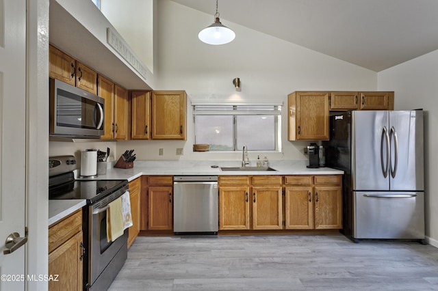 kitchen featuring brown cabinetry, stainless steel appliances, a sink, and light countertops