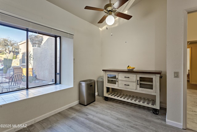 interior space with wood finished floors, a ceiling fan, and baseboards