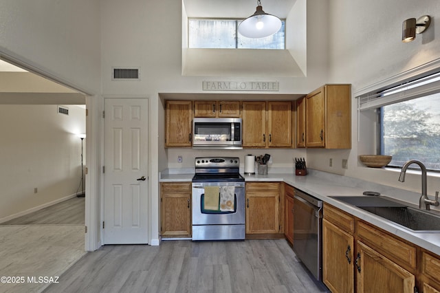 kitchen featuring appliances with stainless steel finishes, visible vents, a sink, and a towering ceiling