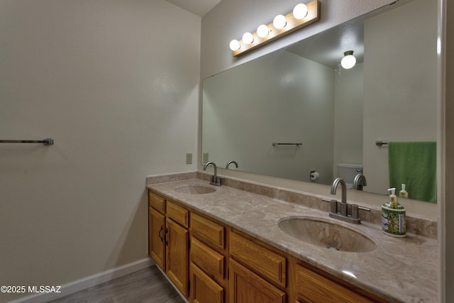 bathroom featuring double vanity, baseboards, toilet, and a sink