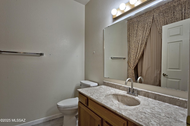 bathroom featuring vanity, toilet, and baseboards