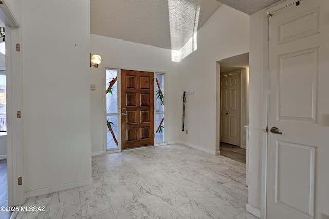 foyer with a textured ceiling, marble finish floor, and baseboards