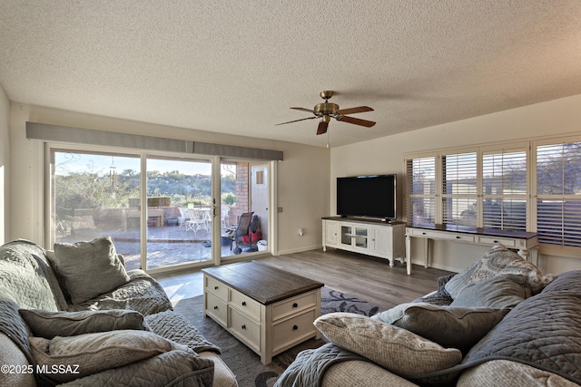 living area featuring ceiling fan, a textured ceiling, baseboards, and dark wood-type flooring