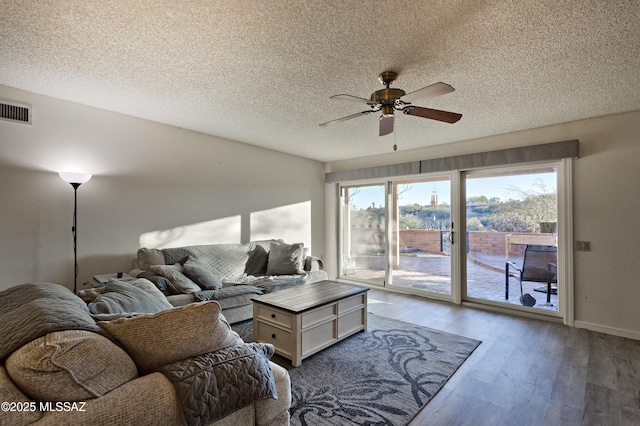 living area with visible vents, ceiling fan, a textured ceiling, wood finished floors, and baseboards