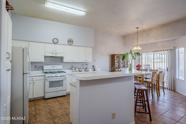 kitchen featuring white cabinets, white appliances, hanging light fixtures, a center island with sink, and a breakfast bar