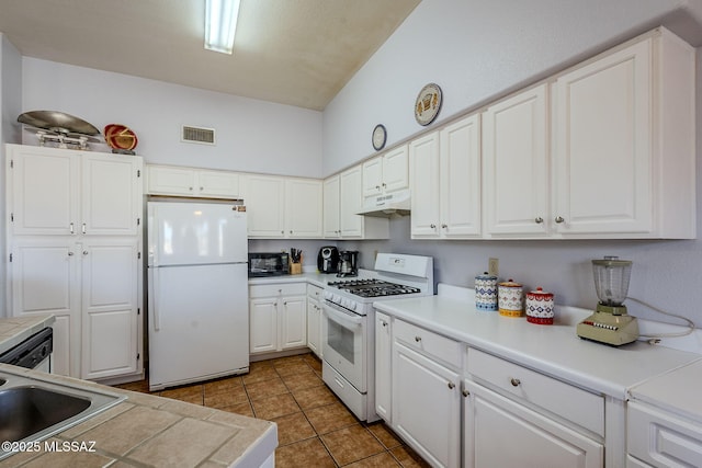 kitchen featuring sink, white appliances, light tile patterned flooring, and white cabinets