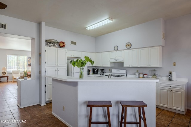 kitchen featuring white appliances, white cabinetry, and a kitchen island with sink