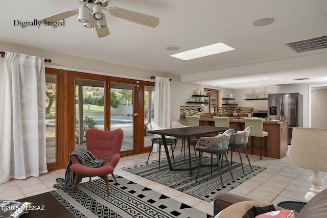 dining area with visible vents, a skylight, a ceiling fan, and light tile patterned flooring