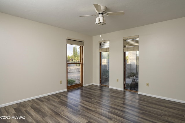 spare room featuring baseboards, a ceiling fan, plenty of natural light, and dark wood finished floors