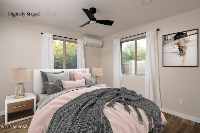 bedroom featuring wood finished floors, a wall mounted air conditioner, baseboards, and multiple windows