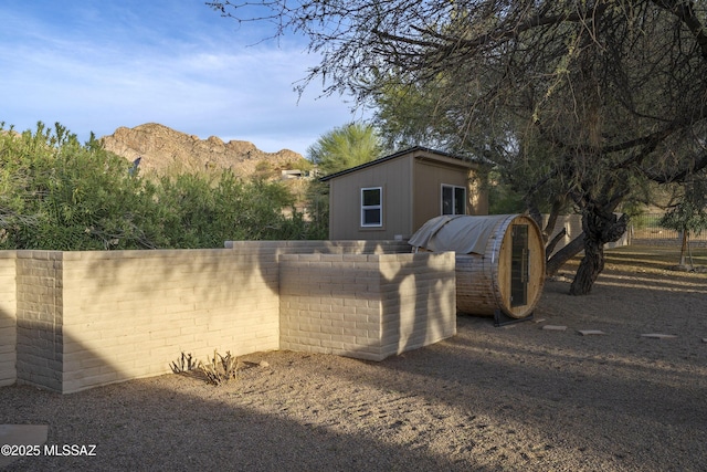 exterior space featuring an outbuilding, a mountain view, and fence