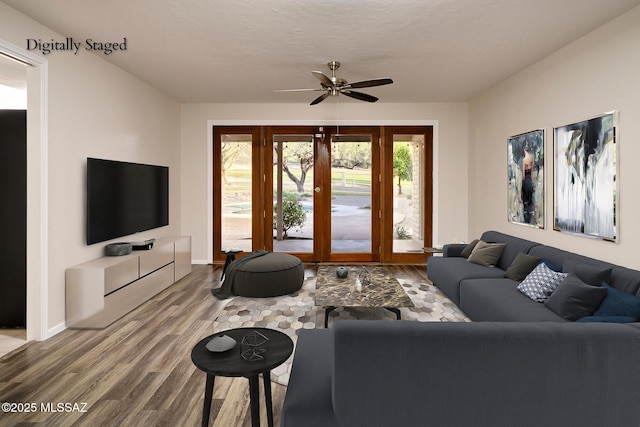 living area featuring ceiling fan, baseboards, and wood finished floors